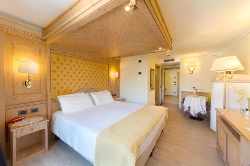a bedroom with a large white bed and a table at Piz Galin Grand Hotel Family & Wellness in Andalo