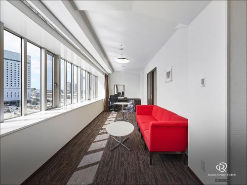 a red couch in a room with windows at Daiwa Roynet Hotel Okayama Ekimae in Okayama