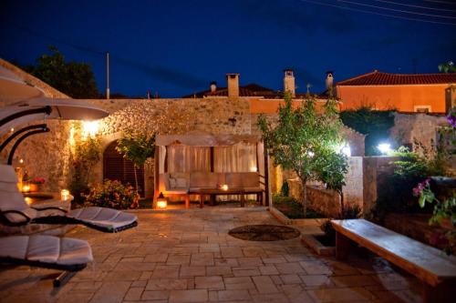 a patio with a table and benches at night at Archontiko Hatzipanayioti in Leonidion