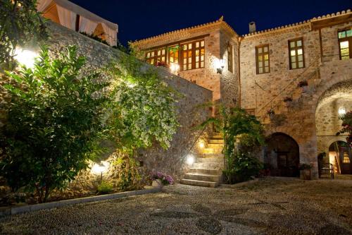 an old stone building with stairs in a yard at night at Archontiko Hatzipanayioti in Leonidion