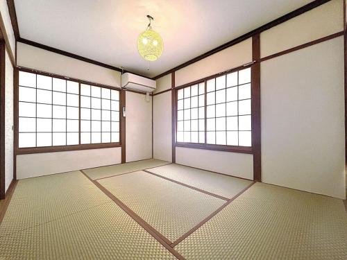an empty room with two windows and a chandelier at リゾートハウス正波2 in Azumino