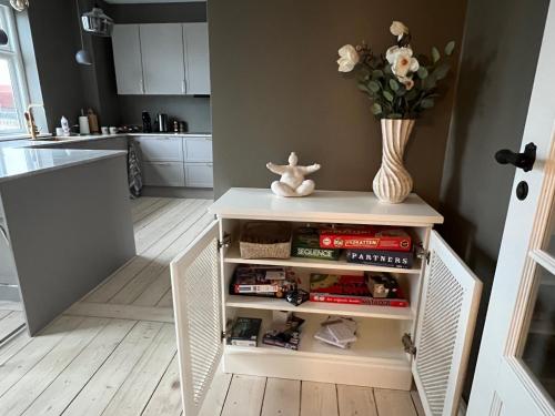 a small white cabinet in a kitchen with a vase of flowers at Byhuset - Hems 60 in Vejle