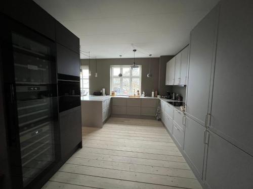 a kitchen with white cabinets and a large window at Byhuset - Hems 60 in Vejle