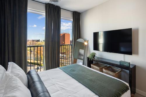a bedroom with a bed and a television and a balcony at Luxury Furnished Apartments by Hyatus Downtown at Yale in New Haven