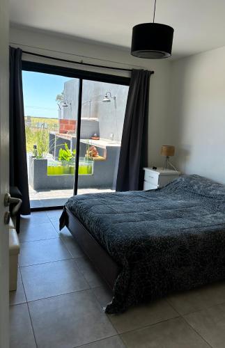 a bedroom with a bed and a large window at Casa Otarina Chapadmalal in Chapadmalal