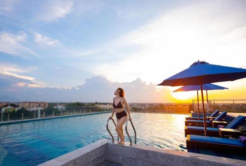 a woman in a bikini standing on the edge of a swimming pool at Le Pavillon Hoi An Paradise Hotel & Spa in Hoi An
