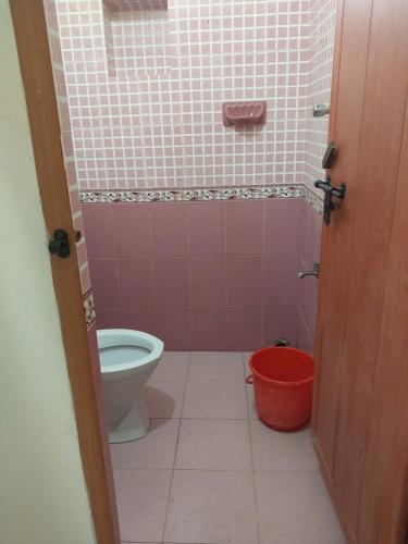 a bathroom with a toilet and a red bucket at Taj Mahal Hotel in Cochin