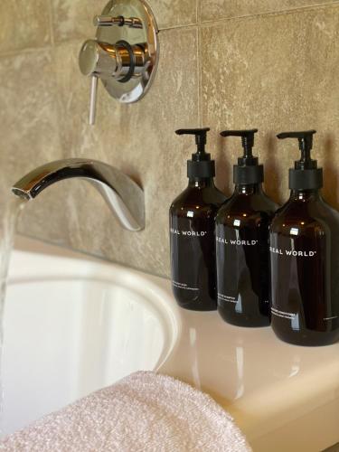 three bottles of soap are sitting on a bathroom sink at Adrift In Golden Bay- Absolute Beachfront Villas in Collingwood
