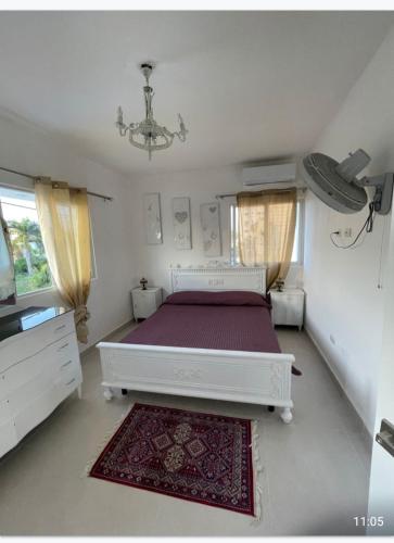 a bedroom with a white bed and a red rug at Villa Vintage. in Boca Chica