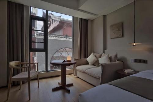 a hotel room with a bed and a couch and a window at Phoenix Hall House Hotel in Fenghuang