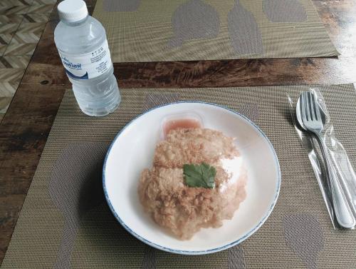 a plate of food with a fork and a bottle of water at คาเฟ่ เดอ แจ่วบอง รูมแอนด์เซอร์วิส in Khon Kaen