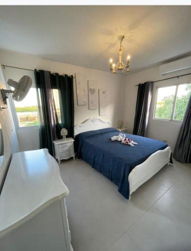 a bedroom with a blue bed and a chandelier at Villa Vintage. in Boca Chica