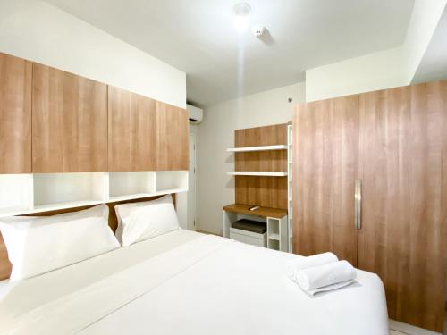a bedroom with a white bed and wooden cabinets at Homey and Nice 3BR at Springlake Summarecon Bekasi Apartment By Travelio in Bekasi