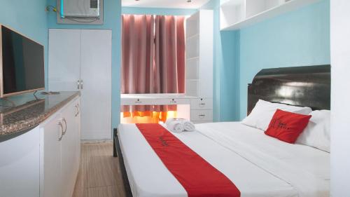 a bedroom with a large white bed with red pillows at RedDoorz at TJMG by Bel Air Polaris Makati in Manila