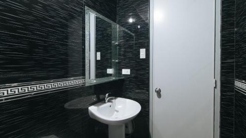 a black and white bathroom with a sink and a mirror at RedDoorz at TJMG by Bel Air Polaris Makati in Manila