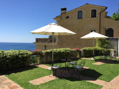 a patio with tables and umbrellas in front of a house at Palazzo Suriano Heritage Hotel in Vietri sul Mare