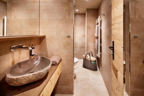a bathroom with a stone sink and a toilet at Lifestyle Hotel eder in Maria Alm am Steinernen Meer