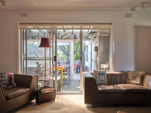 a living room with two couches and a sliding glass door at Warraburra Beach Shack, Rosebud - 2 bedrooms - plus your own private Beach box! in Rosebud