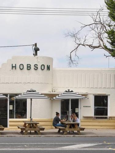 two people sitting at picnic tables in front of a hotel at Warraburra Beach Shack, Rosebud - 2 bedrooms - plus your own private Beach box! in Rosebud