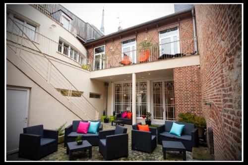 an outdoor patio with black chairs and colorful pillows at Hotel Le Prieuré et La Résidence in Amiens