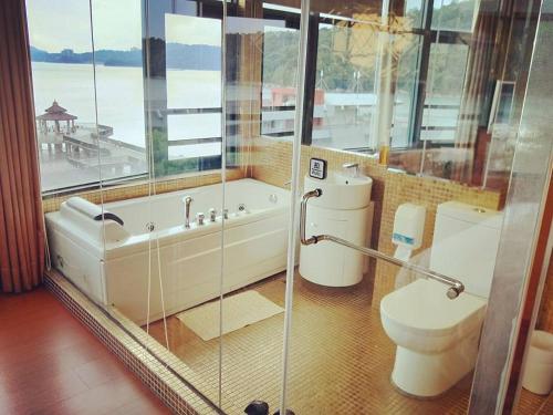 a bathroom with a tub and a toilet and a window at Shuian Lakeside Hotel in Yuchi