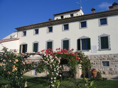 Biały budynek z kwiatami przed nim w obiekcie La Casaccia Guelfi w mieście Castelnuovo Berardenga