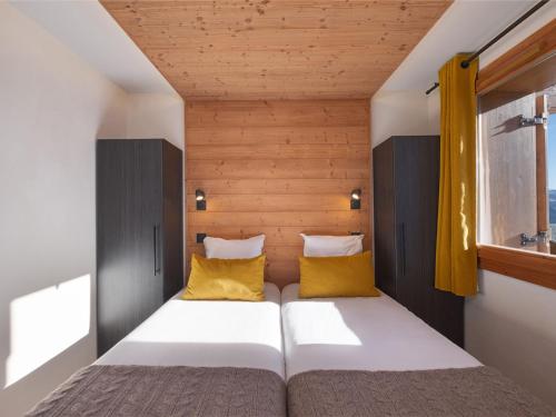 - une petite chambre avec un lit et des oreillers jaunes dans l'établissement Appartement de standing proche des pistes avec accès bien-être et parking couvert - FR-1-809-10, aux Saisies