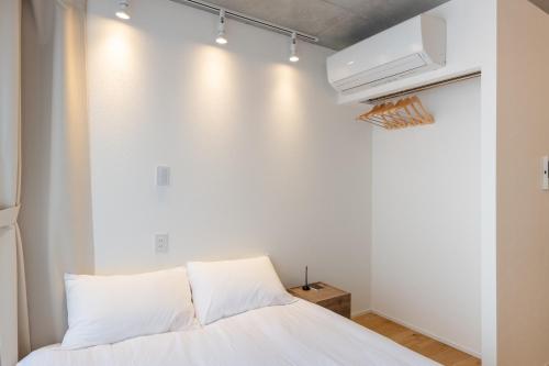 a bedroom with a bed and a white wall at trias 302 in Tokyo