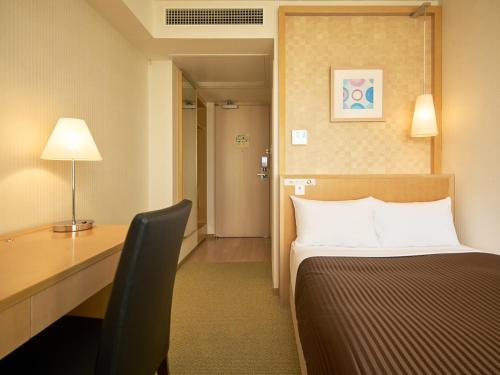 a hotel room with a bed and a desk with a lamp at The OneFive Tokyo Kameido in Tokyo