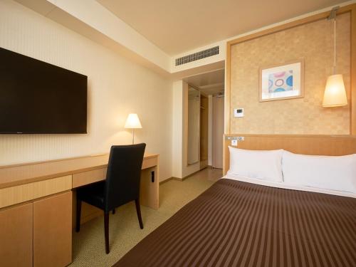 a hotel room with a bed and a desk and a tv at The OneFive Tokyo Kameido in Tokyo