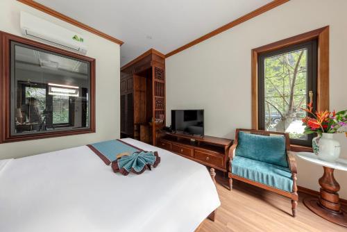 a bedroom with a bed and a tv and a chair at Indochine Boutique Hotel Ninh Bình in Ninh Binh