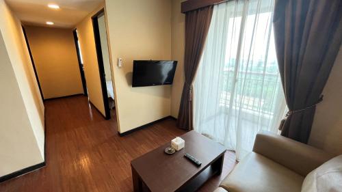 a living room with a couch and a large window at Grand Serpong Hotel in Panunggangah