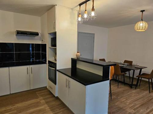 a kitchen with white cabinets and a dining room with a table at T2 cosy avec place de parking in Mamoudzou