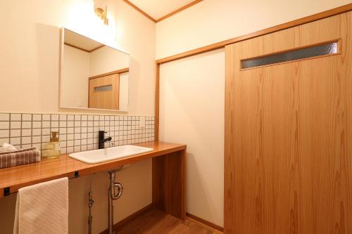 a bathroom with a sink and a wooden door at Tsukasaya Ryokan in Tsuruoka
