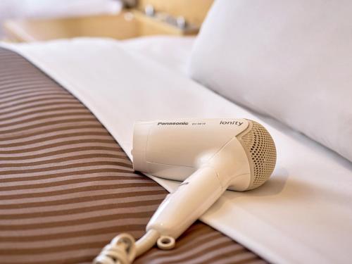 a hair dryer sitting on top of a bed at The OneFive Tokyo Kameido in Tokyo