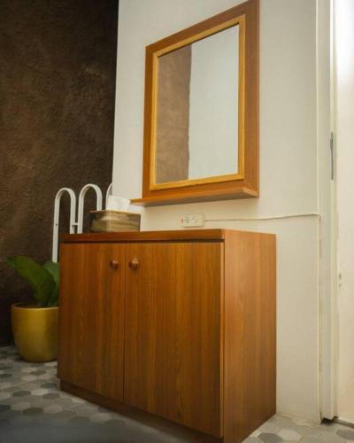 a wooden cabinet with a mirror on a wall at Bylina House in Batu