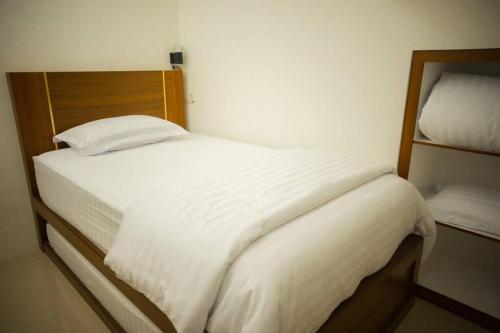 a bedroom with a white bed with a wooden headboard at Bylina House in Batu