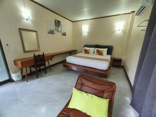 a bedroom with a bed and a desk and a piano at Malulee KhaoSok Resort in Khao Sok