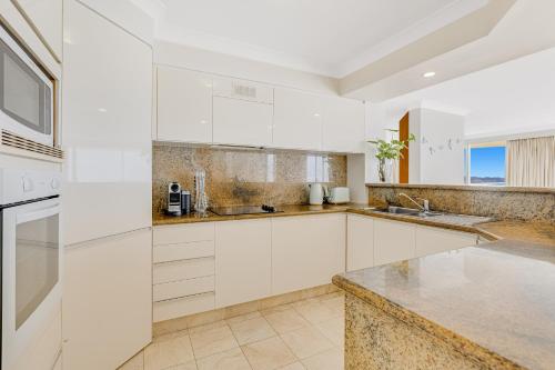 a kitchen with white cabinets and a counter top at Meridian Tower Kirra Beach in Gold Coast