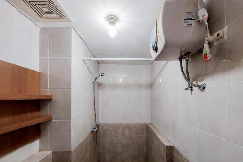 a shower in a bathroom with white tiles at Comfortable and Homey 1BR Apartment at Silkwood Residences By Travelio in Tangerang