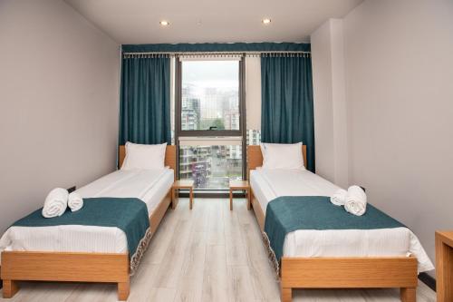 two beds in a room with a window at Marina Green Suite & Residence in Trabzon