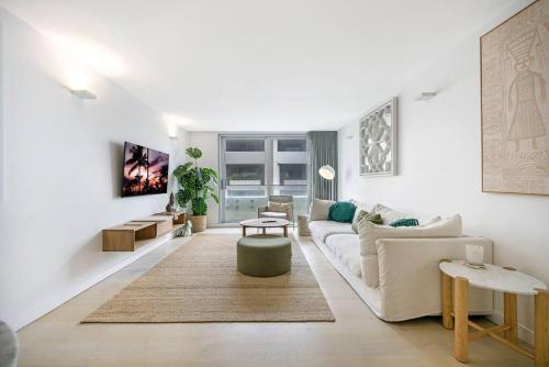 a white living room with a couch and a table at Beach Front Urban 2 Bedrooms in Sydney