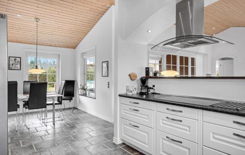 a kitchen with white cabinets and a dining table at Lovely Home In Ørsted With Wifi in Ørsted