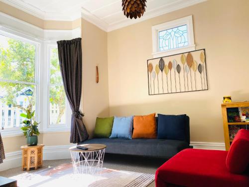 a living room with a blue couch with colorful pillows at In Dunedin's Heart, Full House, Full Sun, Full Chill, Why Stay at a Hotel When You Can Afford an Entire House in Dunedin