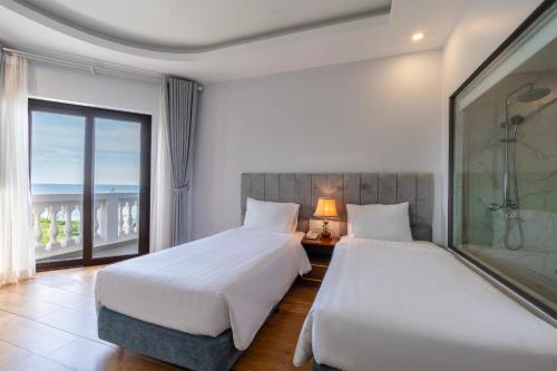 two beds in a hotel room with a window at Maris Beach Hotel Phu Quoc in Phu Quoc