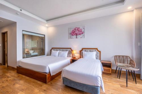 a hotel room with two beds and a chair at Maris Beach Hotel Phu Quoc in Phu Quoc