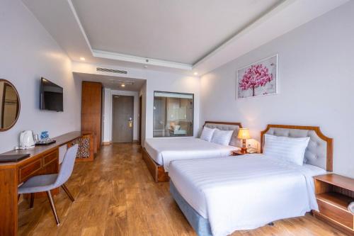 a hotel room with two beds and a desk at Maris Beach Hotel Phu Quoc in Phu Quoc