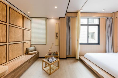 a bedroom with a bed and a chair and a table at Quanzhou West Street Kaiyuan Temple Bandiao Inn in Quanzhou