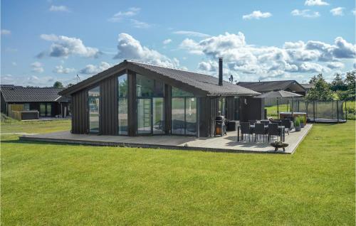a house with glass doors and a deck with chairs at 3 Bedroom Amazing Home In Hørve in Hørve
