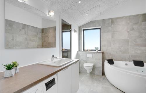 a bathroom with a tub and a toilet and a sink at 3 Bedroom Amazing Home In Hørve in Hørve
